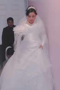 a woman in a wedding dress walking down a hallway