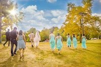 a group of bridesmaids walking in a park