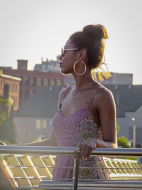 a woman wearing a dress standing on a railing