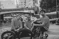 three men in striped shirts sitting on a dock