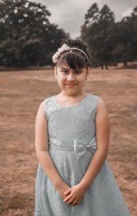 a young girl in a blue dress standing in a field