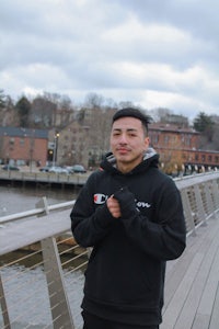 a man in a black hoodie standing on a bridge