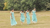 a group of bridesmaids walking in a field