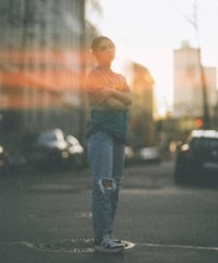 a woman standing in the middle of a street at sunset