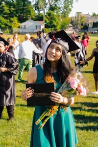 a woman in a graduation gown holding a bouquet of flowers