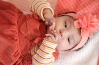 a baby girl in a red dress laying on a blanket