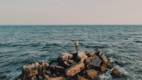 a person standing on a rock in the ocean