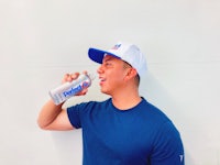 a man in a blue t - shirt drinking from a bottle